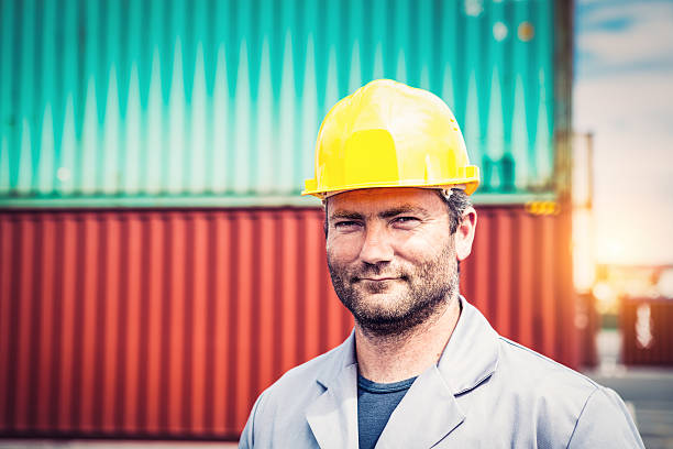 Dock Worker Portrait of a docker with yellow safety helmet in front of containers. koper slovenia stock pictures, royalty-free photos & images