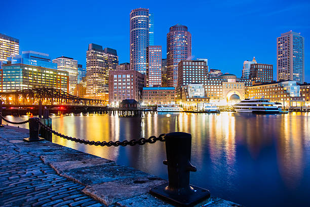 Lights Reflected in Boston's Fan Pier Waterfront at Night The lights of various sizes of buildings are reflected in Boston's Fan Pier waterfront under a clear blue evening sky. A heavy black nautical chain is linked at the pier's edge. boston harbor stock pictures, royalty-free photos & images