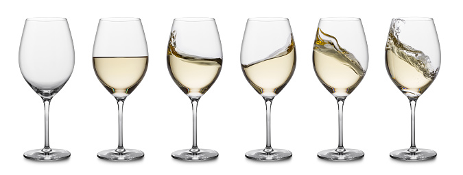 row of white wine glasses, full, empty and with splashes.