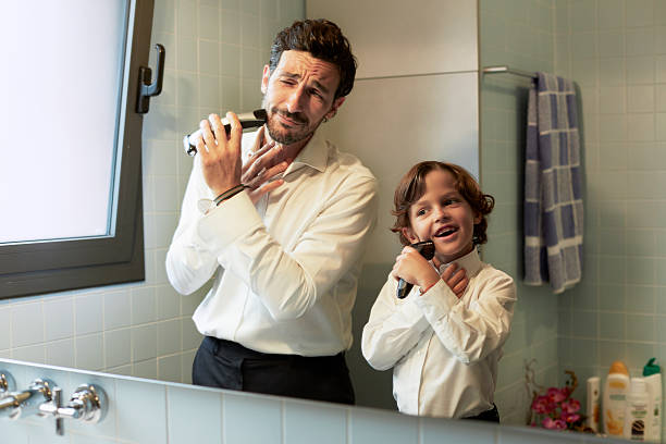 reflection of father and son shaving together - hunky foto e immagini stock