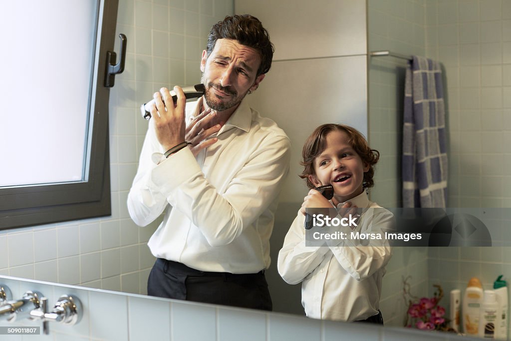 Reflection of father and son shaving together Reflection of father and son shaving together in bathroom Father Stock Photo