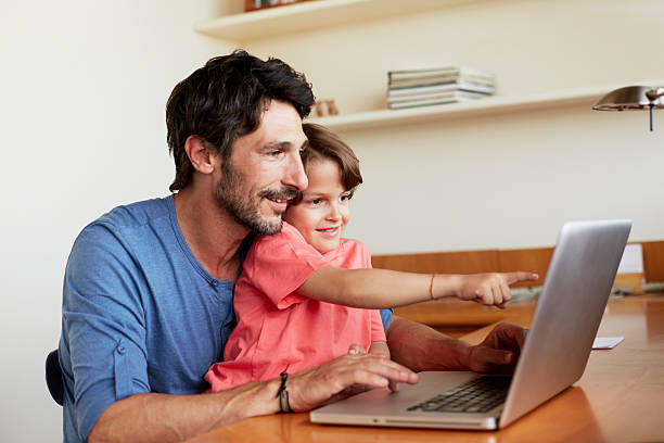 father and son using laptop at table - computer child family laptop foto e immagini stock