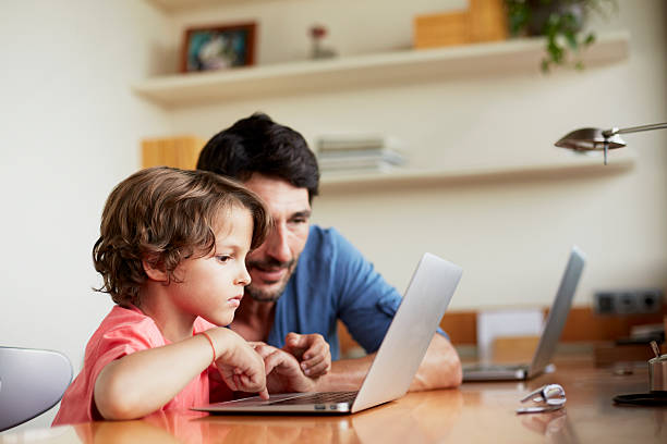 man assisting son in using laptop - computer child family laptop foto e immagini stock