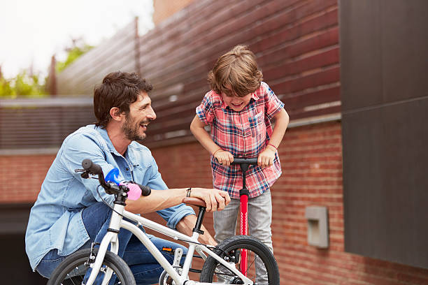 Father looking at son pumping bicycle tire Happy father looking at son pumping bicycle tire outside house air pump stock pictures, royalty-free photos & images