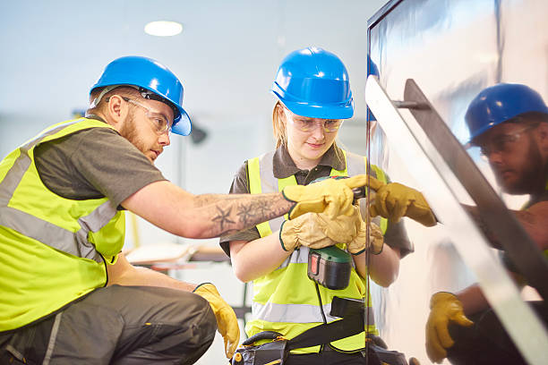 female construction apprentice and colleague a teenage female apprentice carpenter is installing handrails in a modern office refurbishment. She is being supervised by her co-worker . She is using a drill to make guide holes for the hand rails . They are wearing safety workwear. career girl stock pictures, royalty-free photos & images