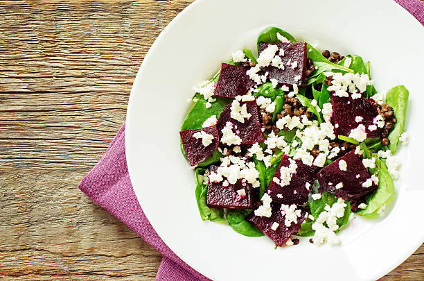 salad with beets, spinach and goat cheese on a dark wood background. tinting. selective focus on the middle of the salad