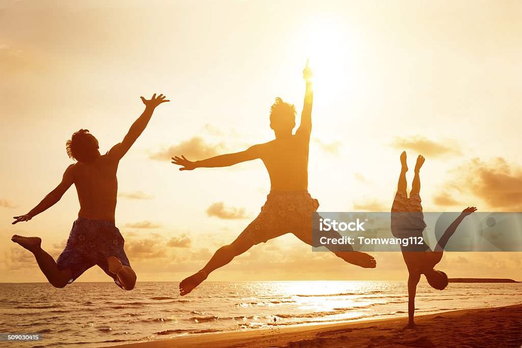 young people jumping on the beach with sunset background Beach Stock Photo