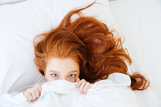 istock Scared woman lying in bed and hiding under the sheet 509030528