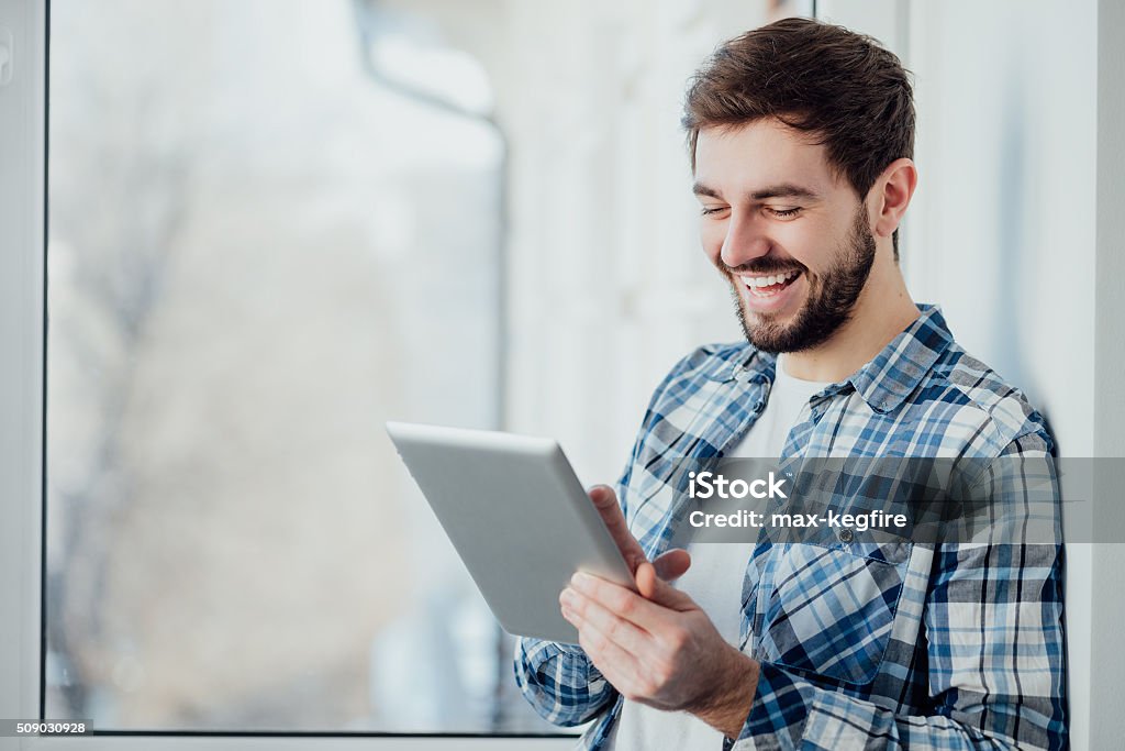 Lächelnder Mann spielt auf Digitaltablett - Lizenzfrei Tablet PC Stock-Foto