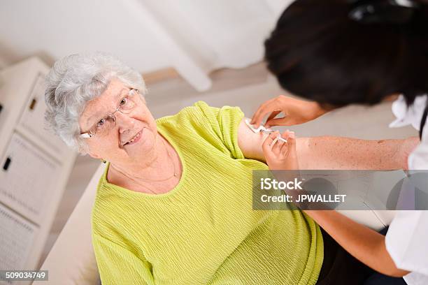 Cheerful Young Nurse Giving Injection To Elderly Woman At Home Stock Photo - Download Image Now