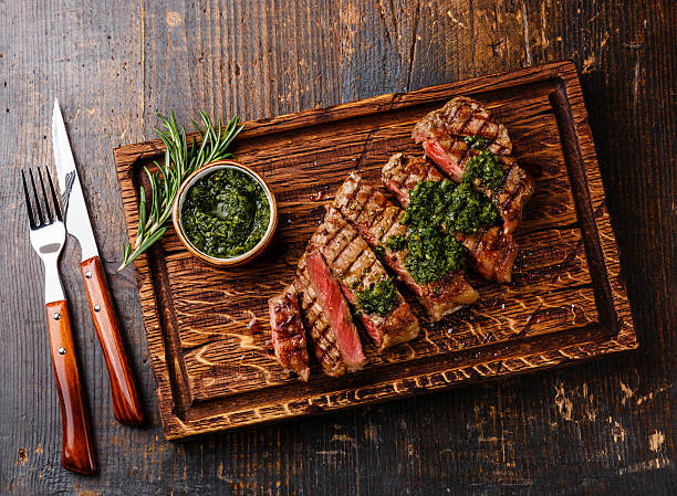Sliced Sirloin steak with chimichurri sauce Sliced medium rare grilled beef barbecue Sirloin steak with chimichurri sauce on cutting board on dark background chimichurri stock pictures, royalty-free photos & images