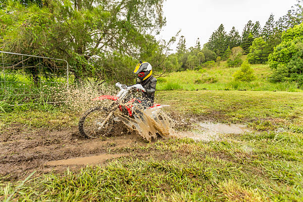 Trail Bike Splashing Through a Mud Puddle on a Farm Trail motorbike splashing through a mud puddle caused by a flooded creek on an Australian farm during a camping holiday bmx racing stock pictures, royalty-free photos & images