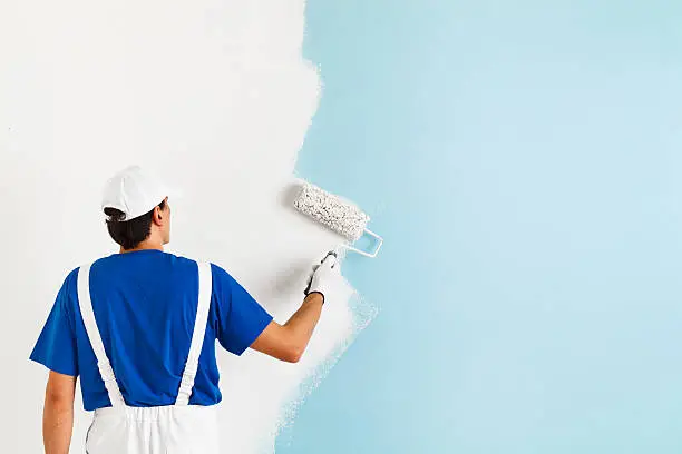 Photo of painter painting a wall with paint roller