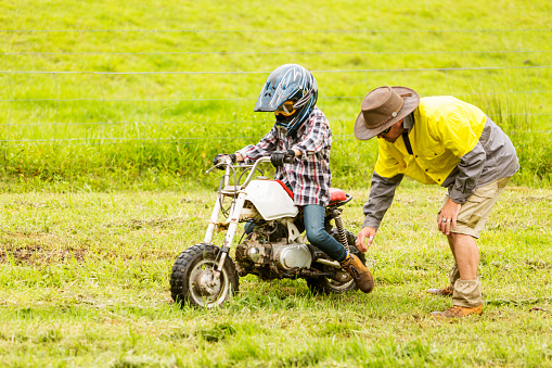 Learner trail motorbike rider being helped out of a bog on an Australian farm during a camping holiday