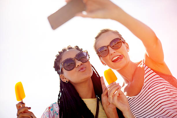 Shot of two young friends eating ice lollies and taking selfies on a summer’s dayhttp://195.154.178.81/DATA/i_collage/pu/shoots/806319.jpg