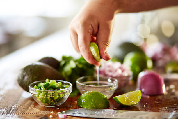 contraindo suco de limão-taiti para guacamole preparação de receitas - guacamole mexican cuisine avocado food - fotografias e filmes do acervo
