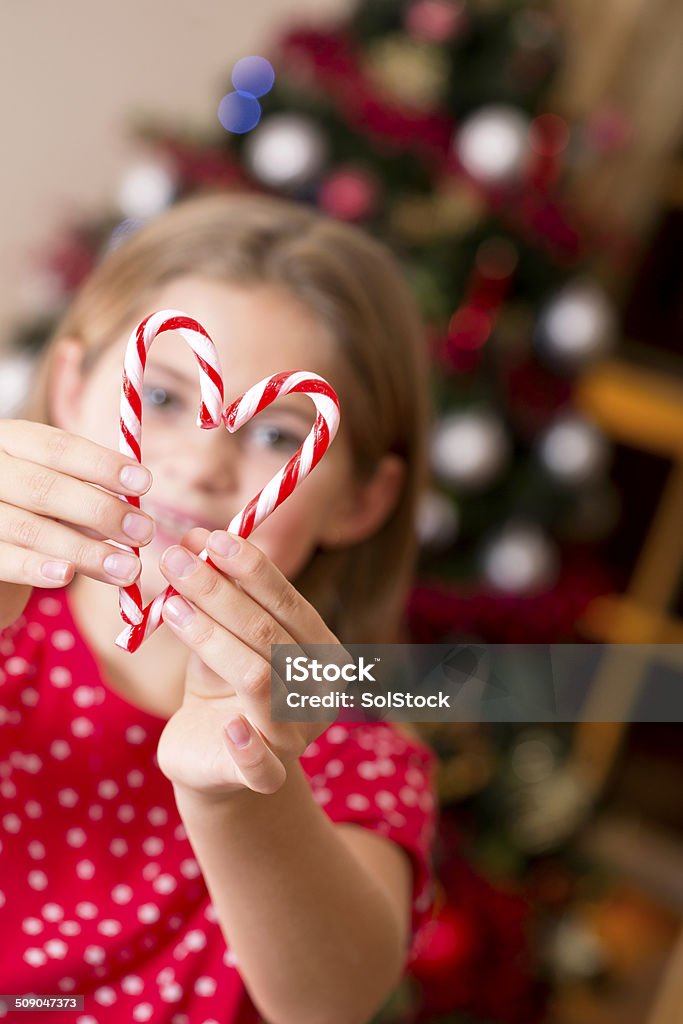 Candy Cane Heart Little girl holds up two candy cane sweets to make a heart shape that she can see through Brown Eyes Stock Photo