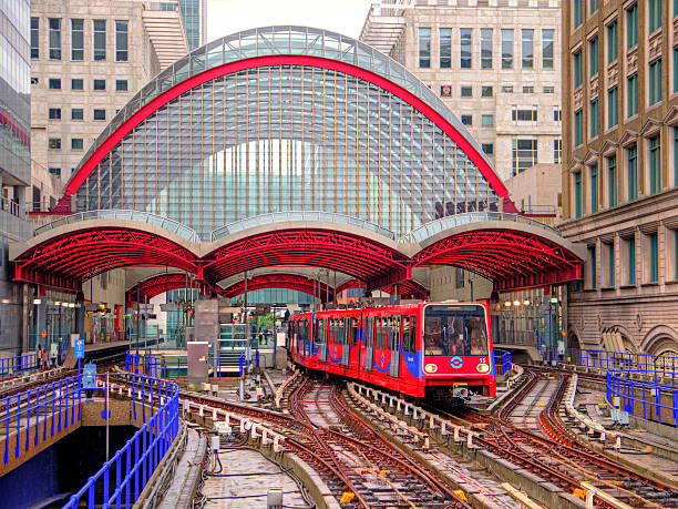 treno dlr parte diverse stazione di canarie wharf a pioggia - docklands light railway foto e immagini stock