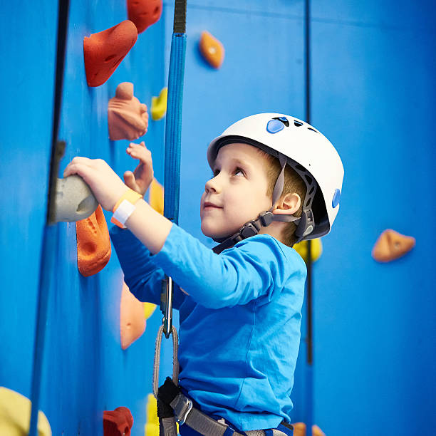 Little boy is climbing in sport park on blue wall Little boy is climbing to amusement park on blue wall clambering stock pictures, royalty-free photos & images