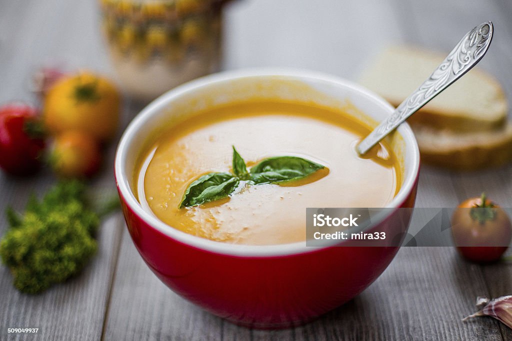 Tomato Soup Fresh tomato soup with basil, and some tomatoes, parsley, garlic, bread on background. Basil Stock Photo
