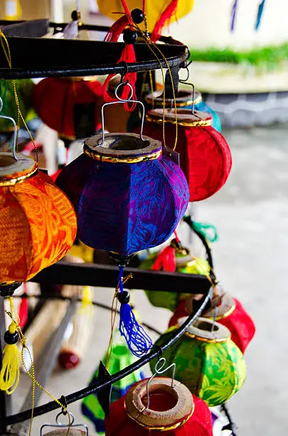 big number of different colored small and round handmade silk lampoons hanging from a metal rack (Vietnam)