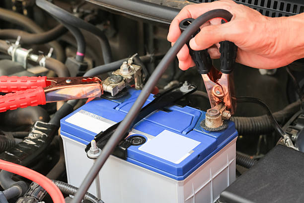 istock Car mechanic uses battery jumper cables charge a dead battery. 509053220
