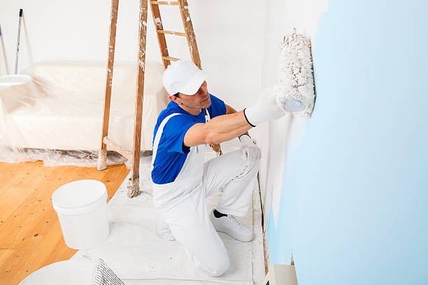 painter painting a wall with paint roller stock photo