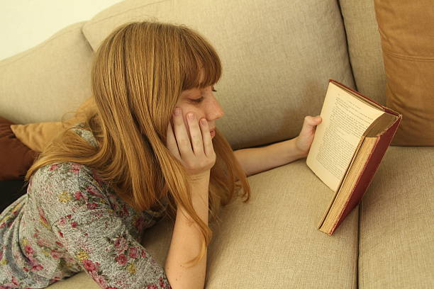 istock Young woman reading on couch 509075927