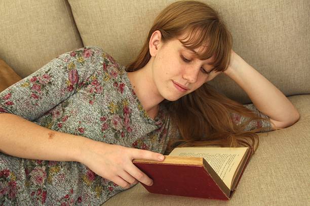 istock Young woman reading on couch 509082735