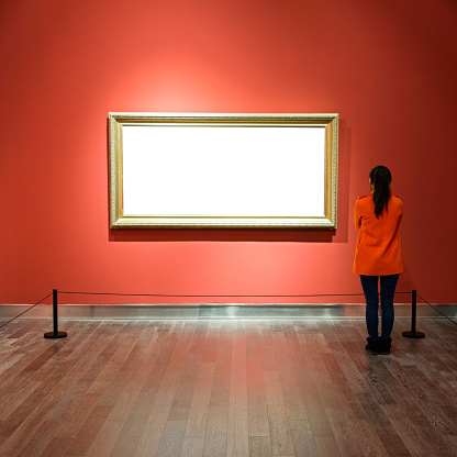 Young asian woman looking at white frames in an art gallery.