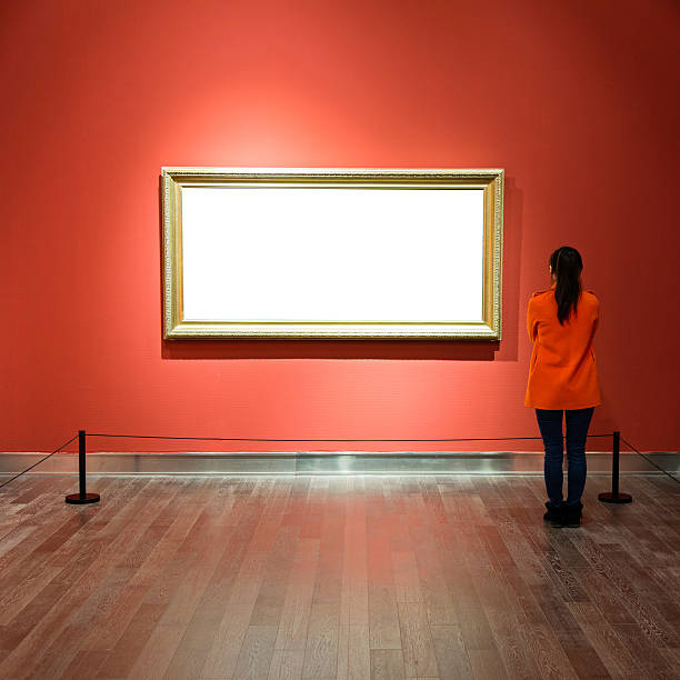 Young woman looking at artwork Young asian woman looking at white frames in an art gallery. hanging art on wall stock pictures, royalty-free photos & images