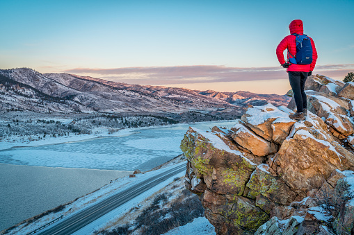 male hiker  contemplating winter  sunrise over frozen Horsetooth Reservoir  at Rocky Mountains foothills near Fort Collins, Colorado