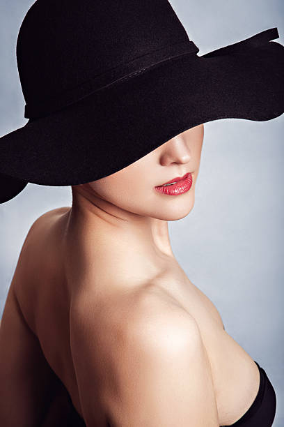 istock Woman in black dress and hat with bare shoulders 509094230