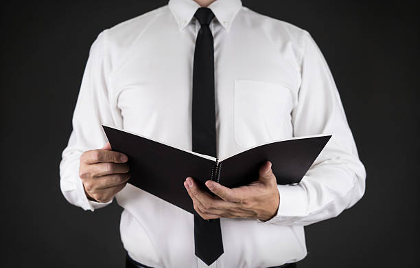 istock Businessman holding note book in his hand with black background 509095444