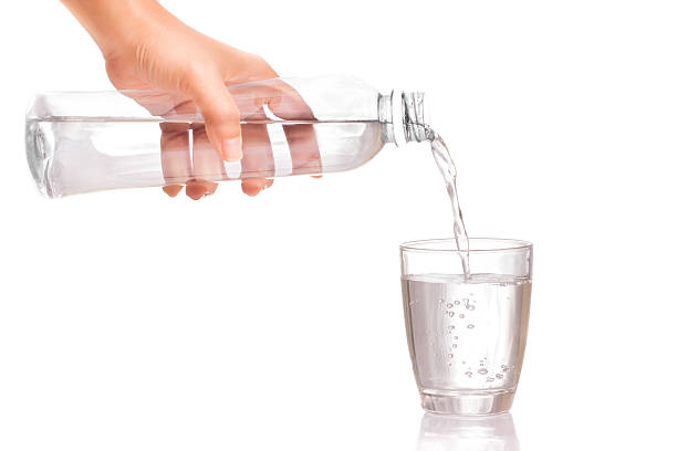 Pouring water into a glass Woman's hand holding a bottle of water Pouring water into a glass pouring water from bottle stock pictures, royalty-free photos & images