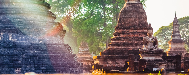 Ancient Stupa with a statue of Buddha in Sukhothai, Thailand. Twilight time.