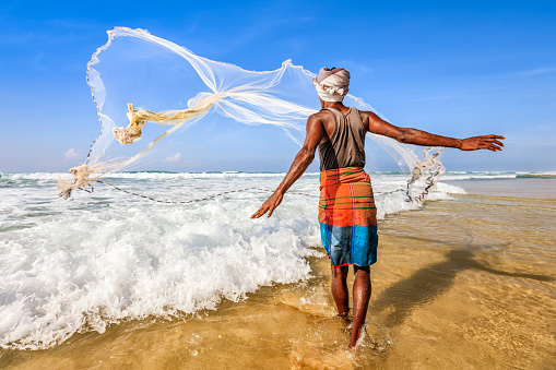 Sri Lankan fisherman throwing a fishing net, beach near Mirissa, A cast net or a throw net, is a net used for fishing. It is a circular net with small weights distributed around its edge.
