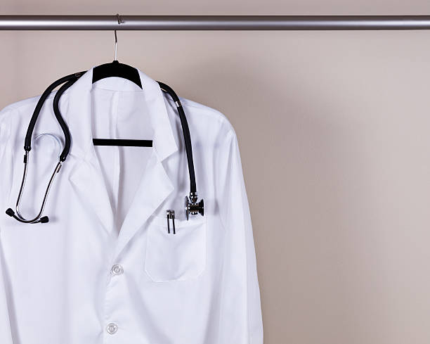 Medical white consultation coat with stethoscope and pens on han stock photo