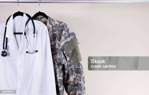 Medical White Consultation Coat And Military Uniform On Hanger Stock Photo - Download Image Now