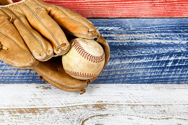 istock Old worn baseball mitt and ball on faded boards 509111438