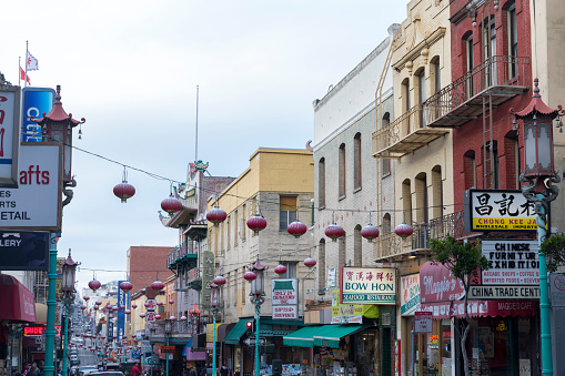 View of the main street of the chinatown district, traffic of cars and people in a cloudy day.