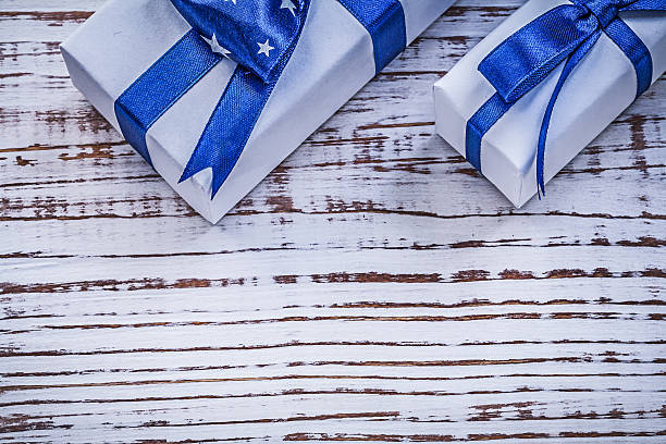 istock Gift containers with blue present bows on vintage wooden board 509118270