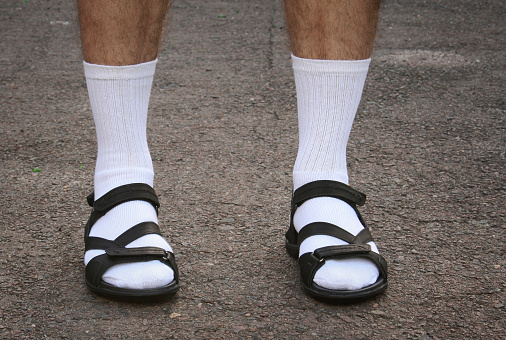 The lower part of men's feet in white socks and sandals