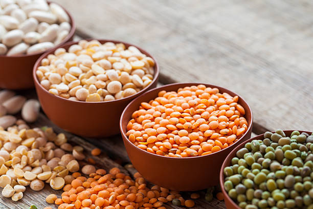 Bowls of cereal grain Bowls of cereal grains: red lentils, green mung, corn, beans and peas on wooden kitchen table. Selective focus. red mung bean stock pictures, royalty-free photos & images