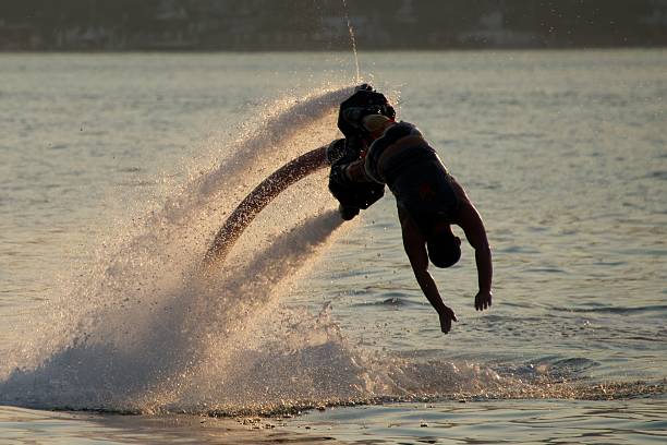 istock Flyboarder in silhouette diving into evening sea 509135151