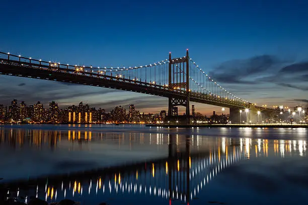 the R.F.K. Bridge, also known as the Triboro Bridge and tunnel with manhattan city in the background at night.