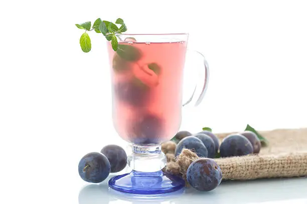 cold plum drink in a glass on a white background