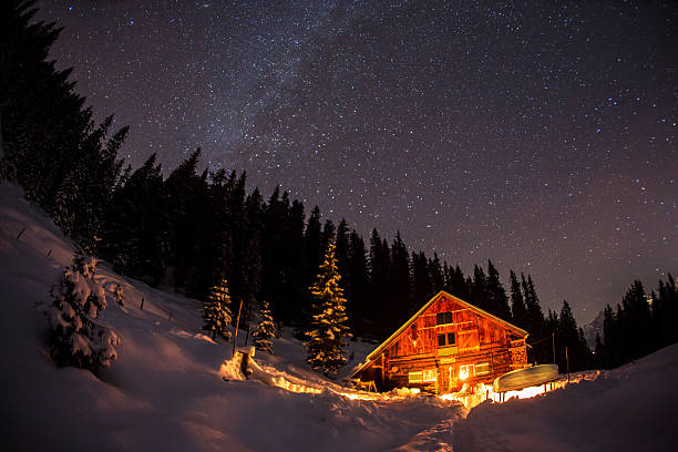 Lightened mountain hut in the Austrian alps with milky way. Scenic winter landscape. Night shot with 3200 ISO.