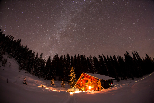 Lightened mountain hut in the Austrian alps with milky way. Scenic winter landscape. Night shot with 3200 ISO.