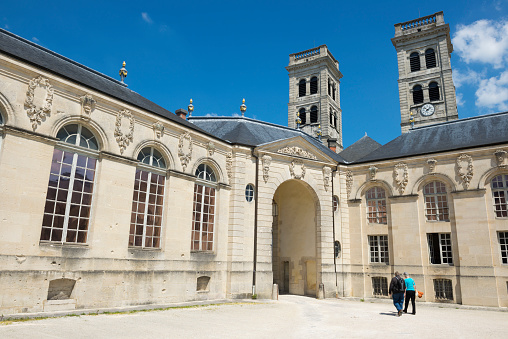 Verdun, France - May 17, 2014: Two people walk in the courtyard of the Centre Mondial de la Paix in Verdun, France. The towers of the Verdun Cathedral are in the background.